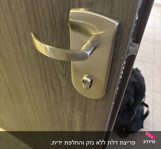 ידית דלת מתכתית על דלת עץ
